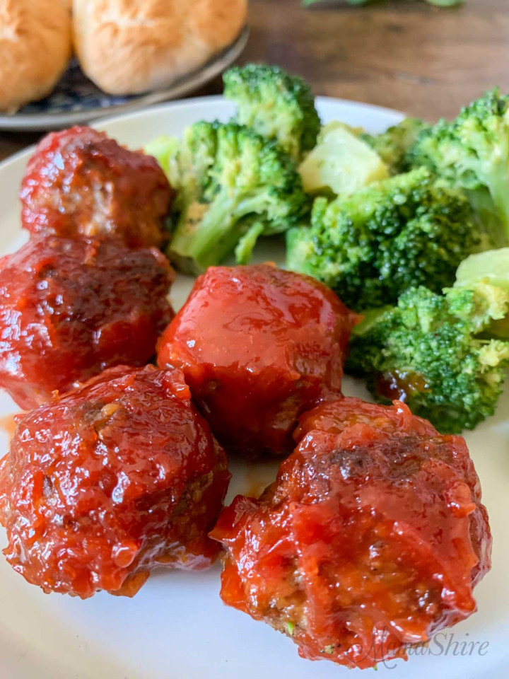 A serving of air fryer BBQ meatballs on a plate with cooked broccoli.