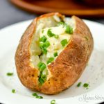 Air fryer baked potatoes with butter and chives.