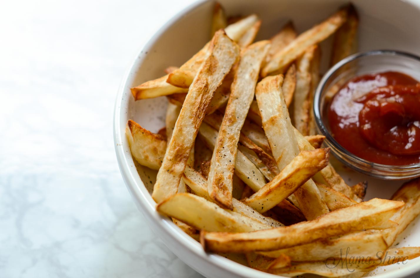 A serving of french fries and ketchup in a white bowl.