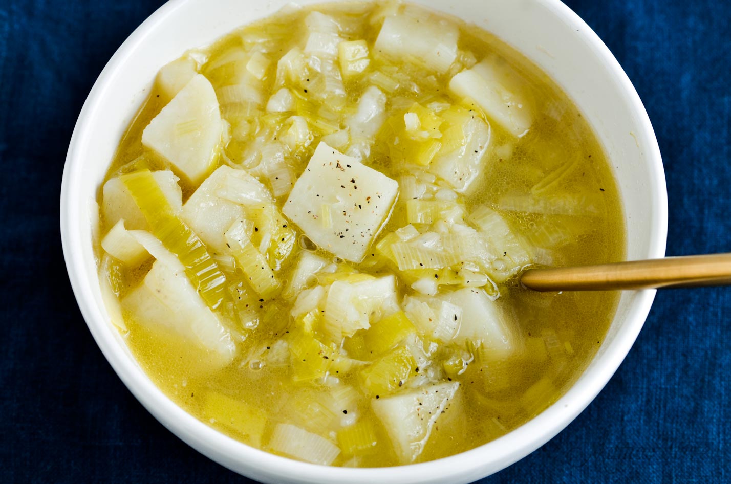 A white bowl full of leek and potato soup.