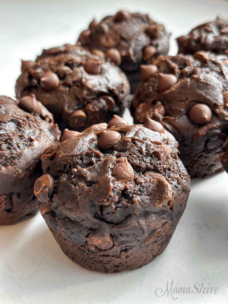 Several gluten-free chocolate muffins on a white base.