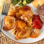 A white dinner plate with fried potatoes, sauerkraut, broccoli, and hamburger.