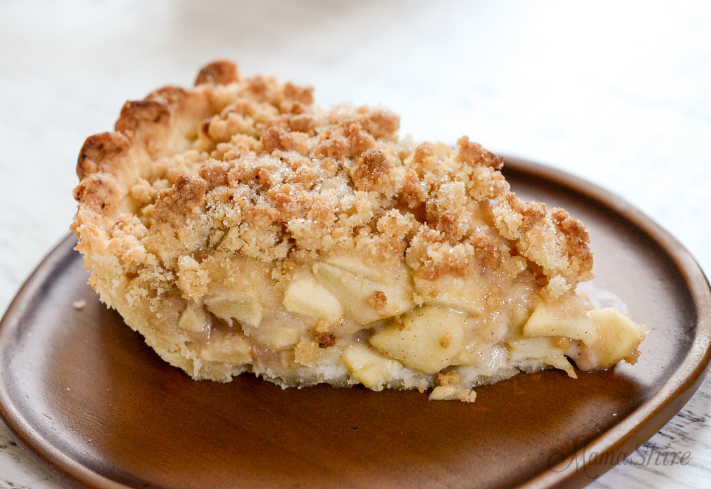 One slice of a Dutch apple pie made from a gluten-free recipe. It has a streusel topping on top of the apples instead of a second crust.