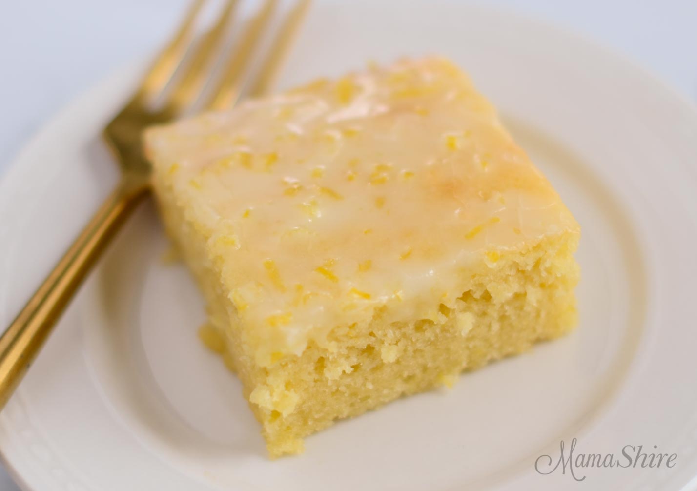 A serving of gluten-free lemon brownies topped with a lemon glaze.