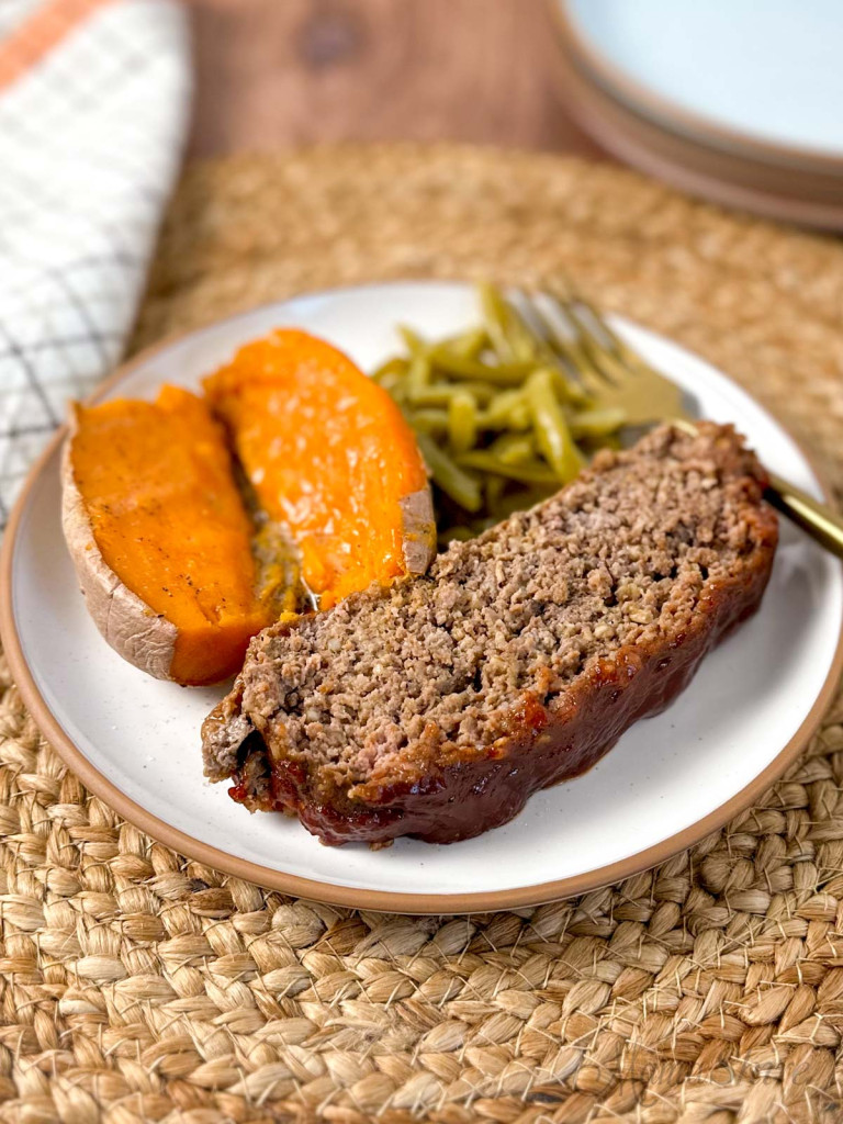 A slice of gluten-free meatloaf with a serving of green beans and sweet potato.