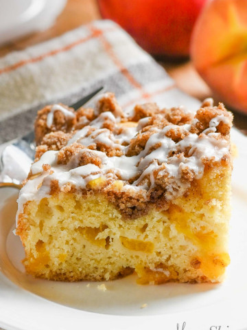 A serving of gluten-free peach coffee cake that has a streusel topping with a glaze over the top.