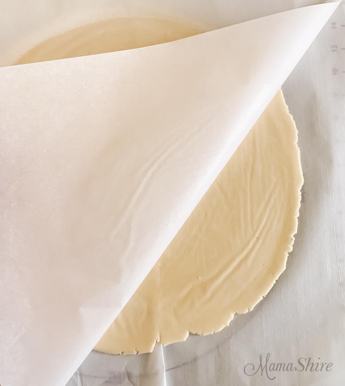 Gluten-free pie crust rolled out with parchment paper.