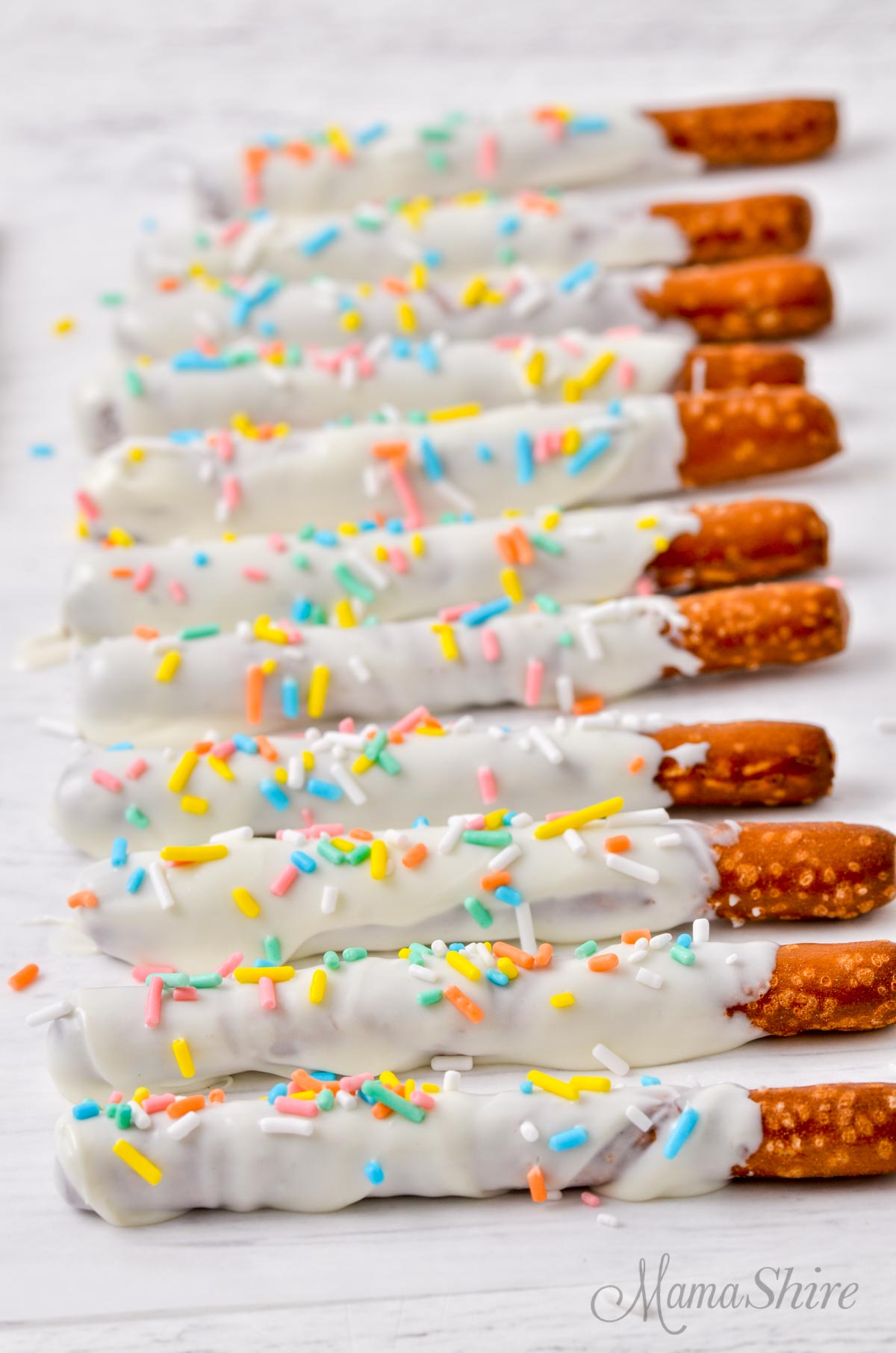 Gluten-free pretzel rods with icing and sprinkles all lined up.