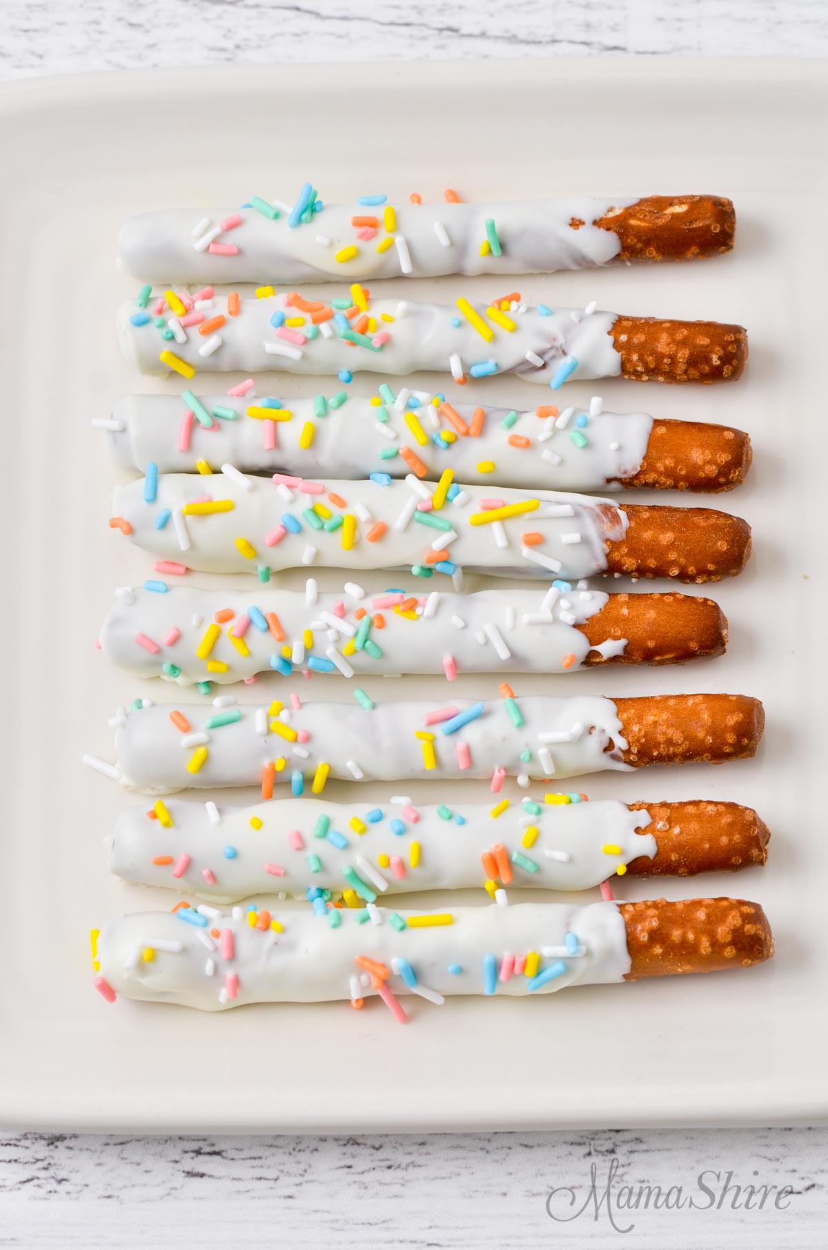 Gluten-free pretzel rods dipped in melted store-bought icing with pastel colored sprinkles.