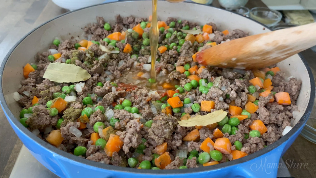 Mixing peas and carrots into the beef mixture for a shepherd's pie (cottage pie).