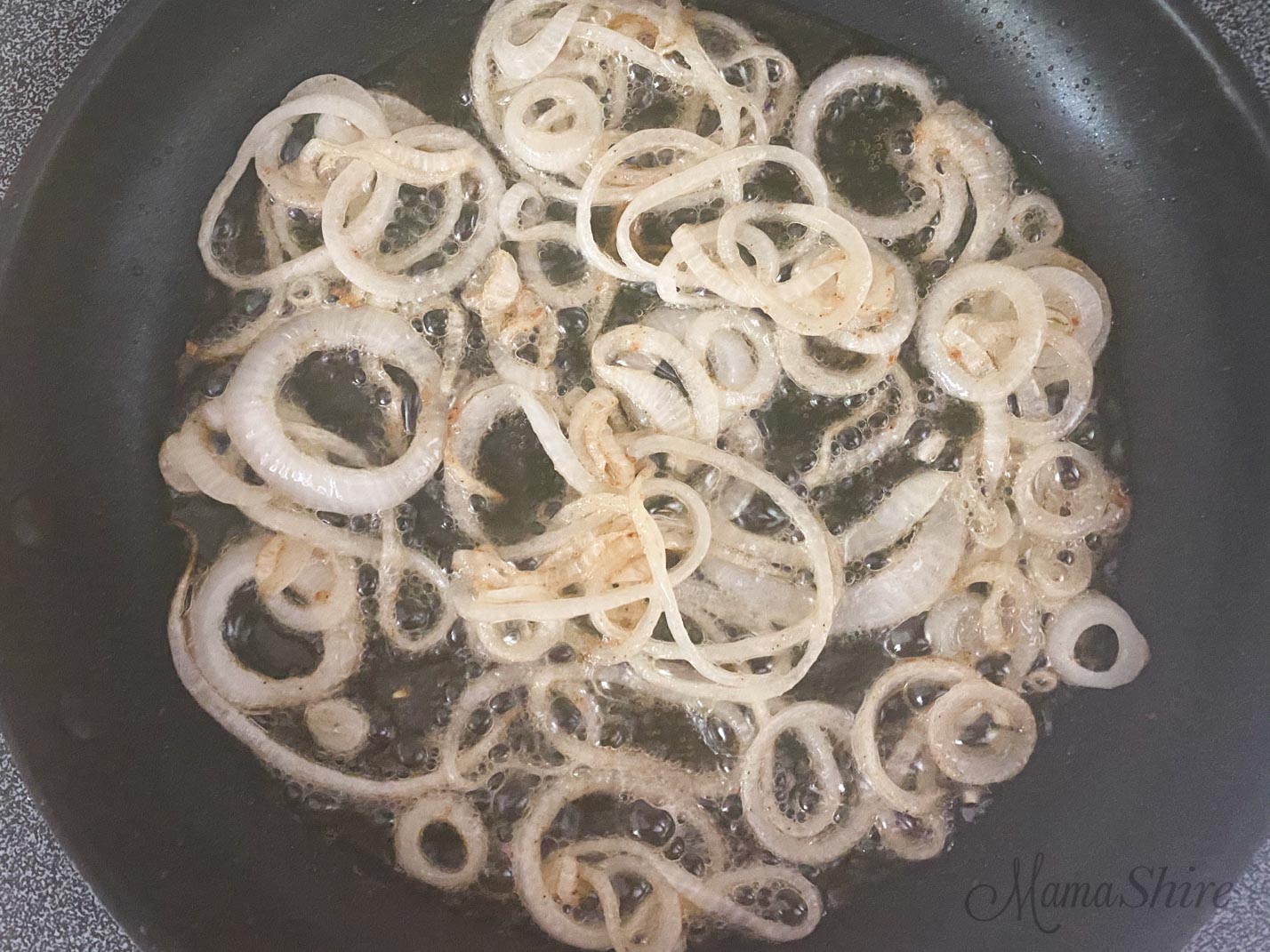 Sliced onions frying in a skillet.
