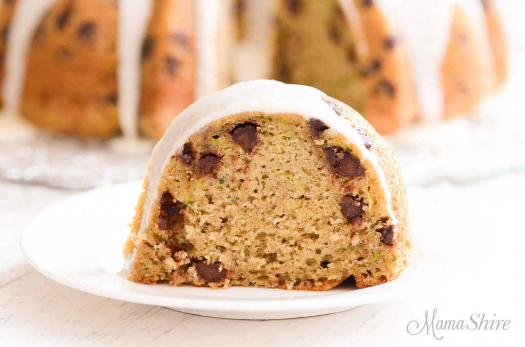 A slice of gluten-free zucchini cake with chocolate chips and icing.