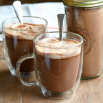Two glass mugs filled with hot cocoa and homemade marshmallows and a jar of dairy-free hot chocolate mix.