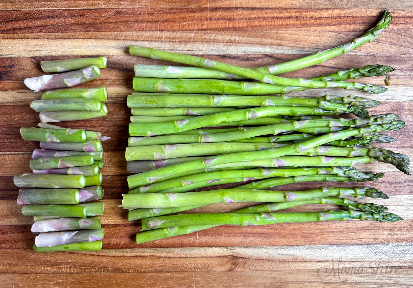 Asparagus on a cutting board with the bottom 2 inches cut off. 