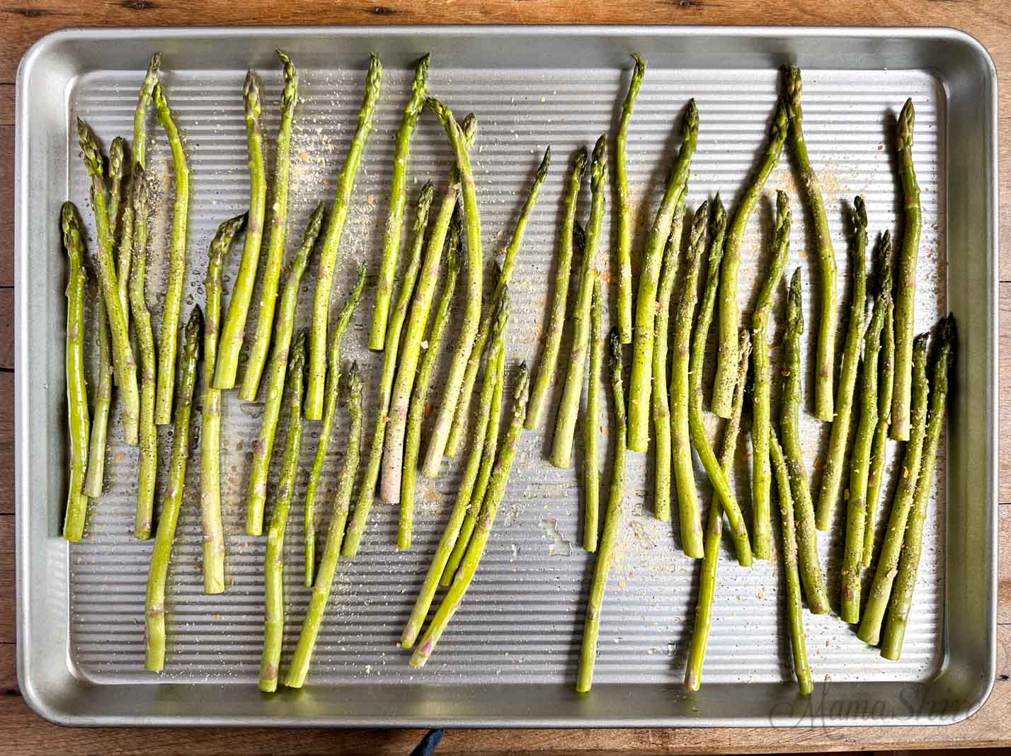 Asparagus seasoned with salt and pepper on a baking pan.