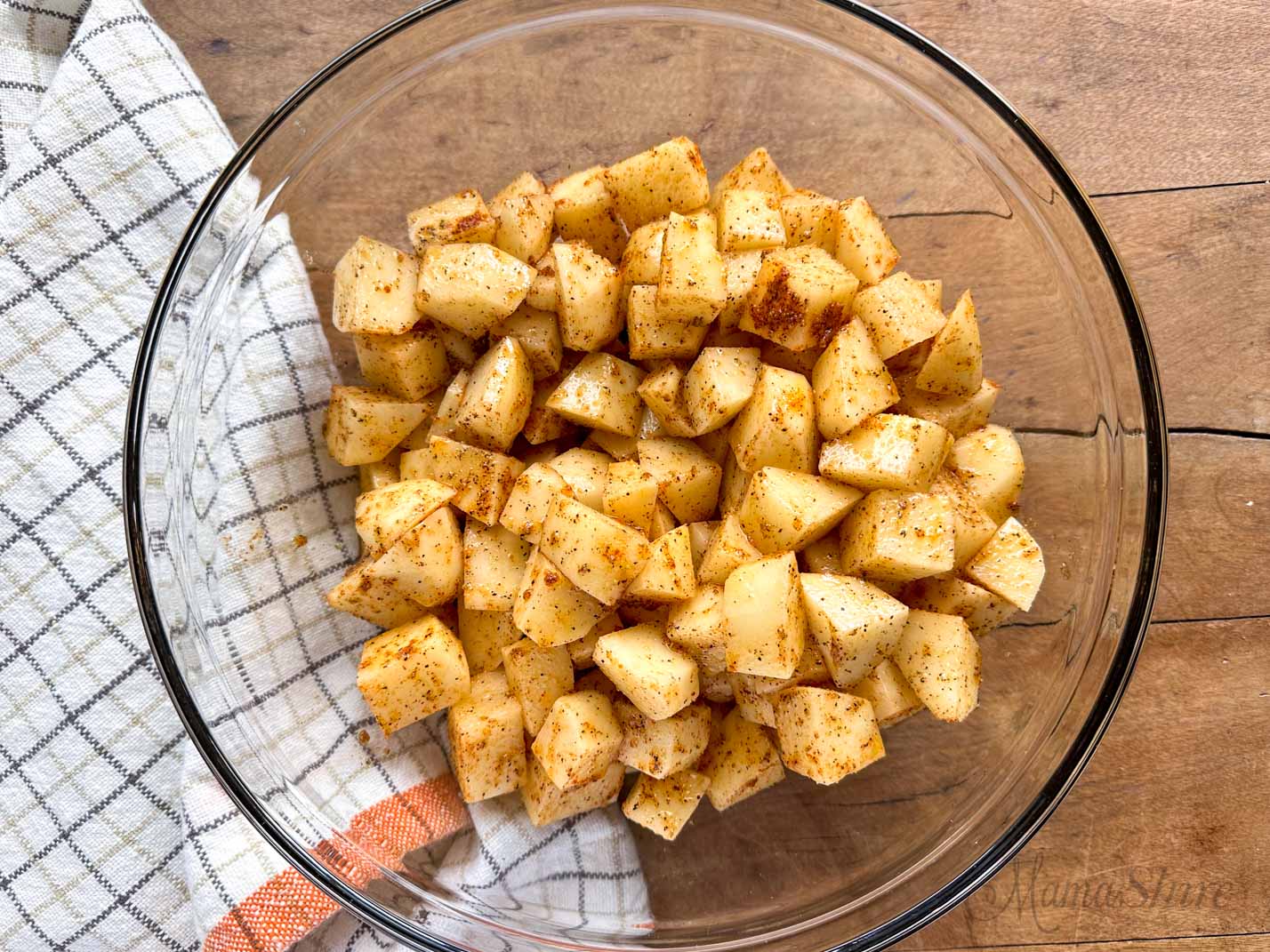 A mixing bowl with diced potatoes and seasoning.
