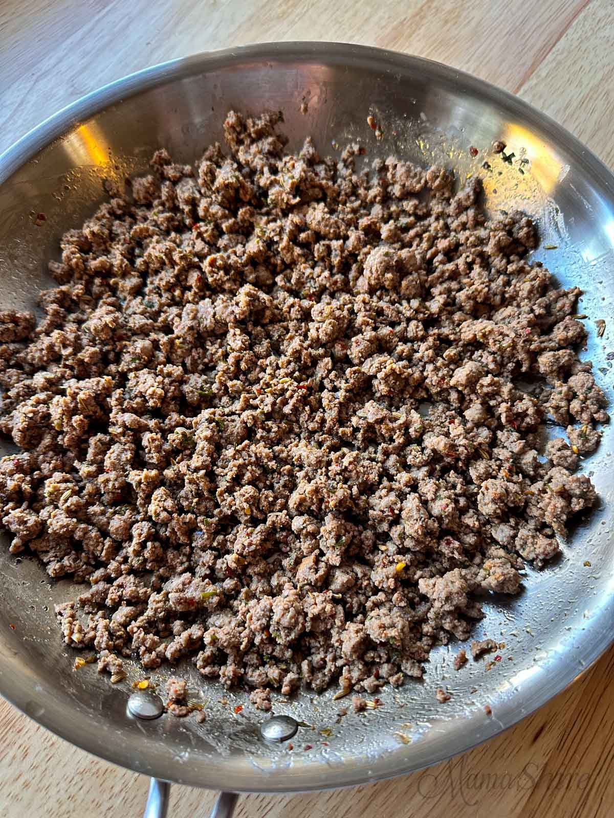 Homemade Italian beef sausage in a stainless steel pan.