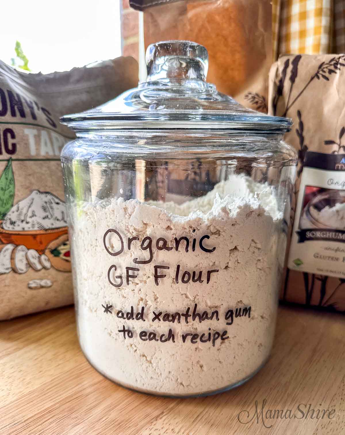 A glass gallon jar of organic gluten-free flour mix. 