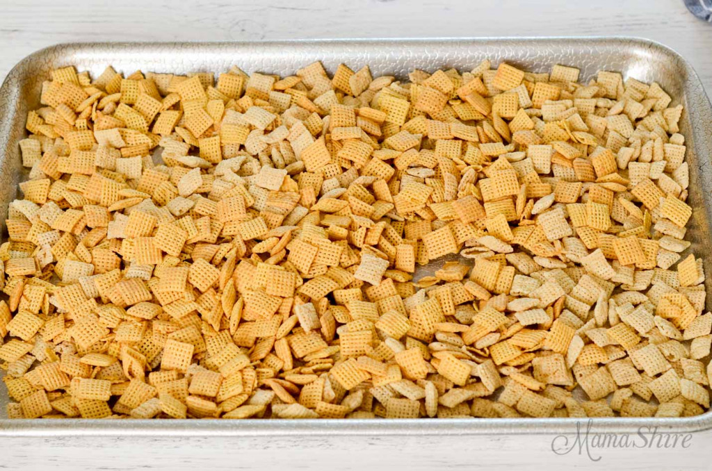 A large baking pan with rice and peanut butter chex cereal spread out.