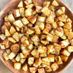 A serving bowl of crispy oven roasted potatoes.