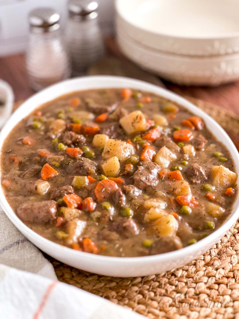 A large serving dish full of gluten-free beef stew that was made in a slow cooker. 
