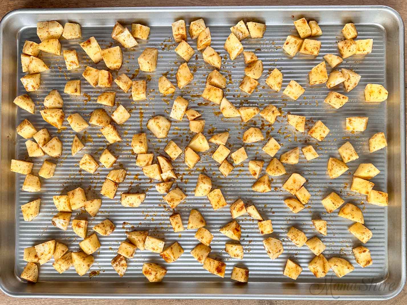 A large baking pan with diced seasoned potatoes to make roasted potatoes.